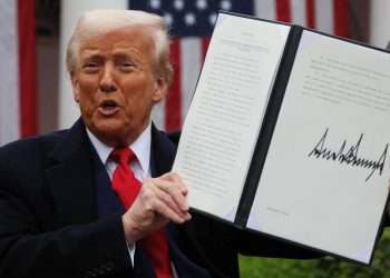 Donald Trump holding a Tariffs card during the April 2025 Rose Garden announcement of sweeping trade measures.